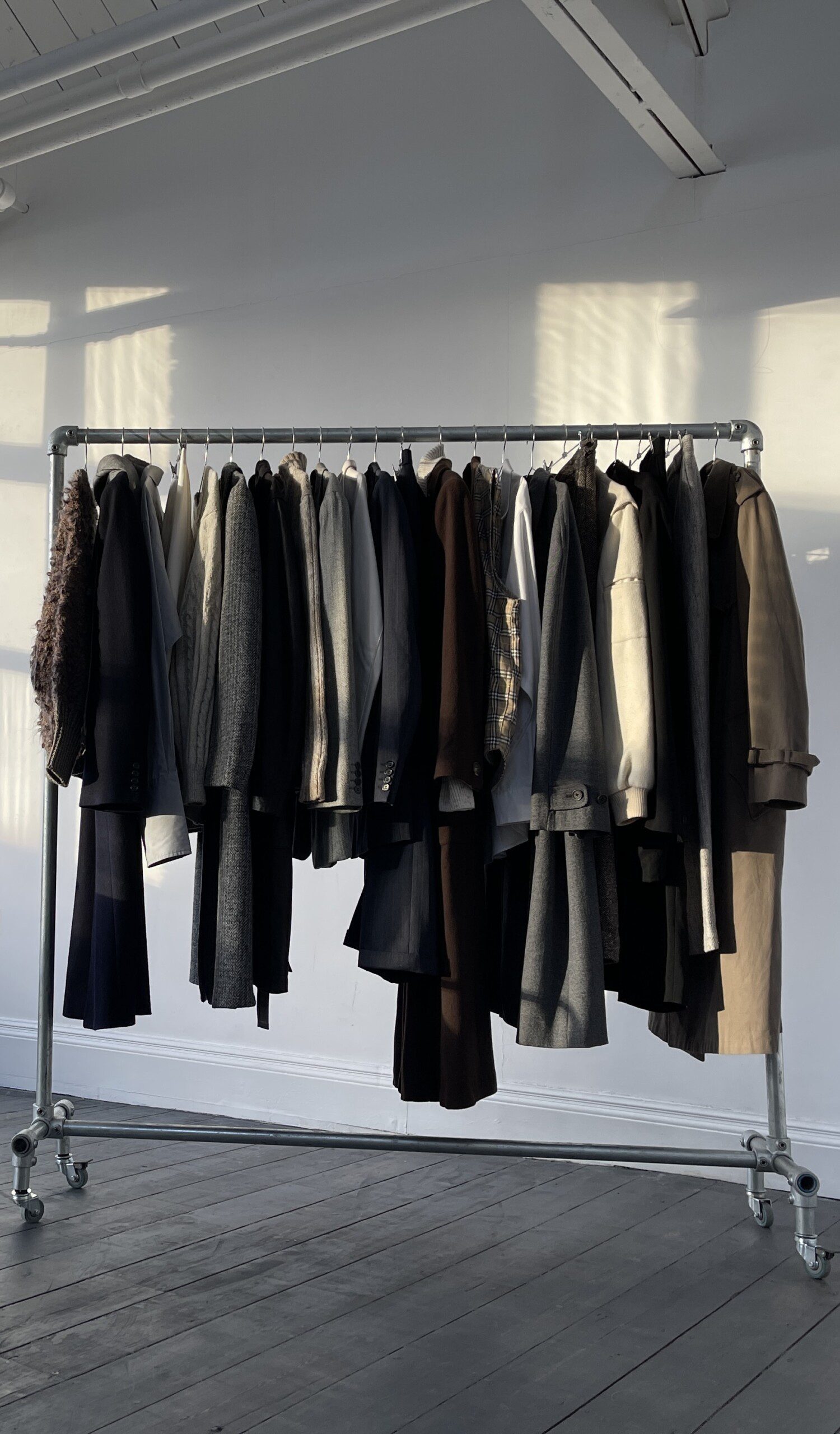 A number of clothing items hanging on a clothes rail, of assorted colours